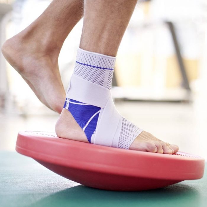 someone balances on one foot with a compression sleeve on their ankle.