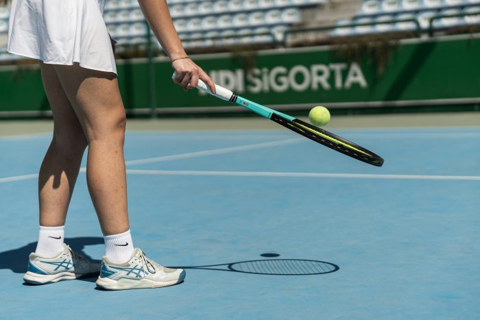 A tennis player bouncing a ball on their racquet