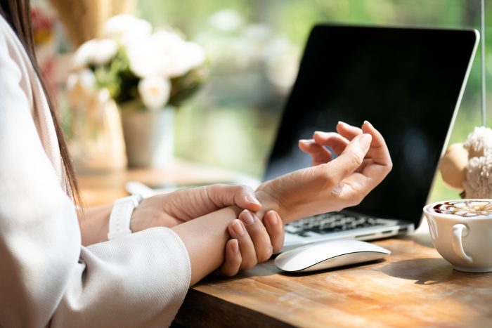 a woman holding her wrist in discomfort due to carpal tunnel syndrome