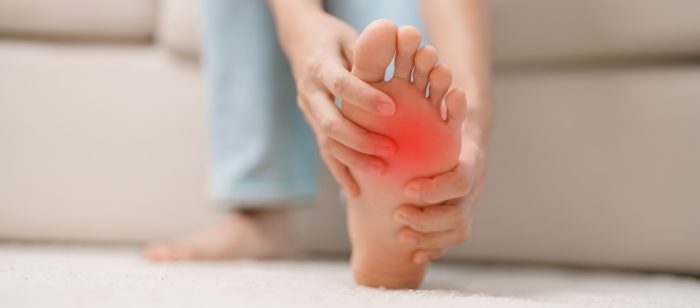 a person holding their foot in pain with plantar fasciitis