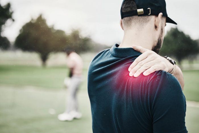 A golfer holding his shoulder in pain.