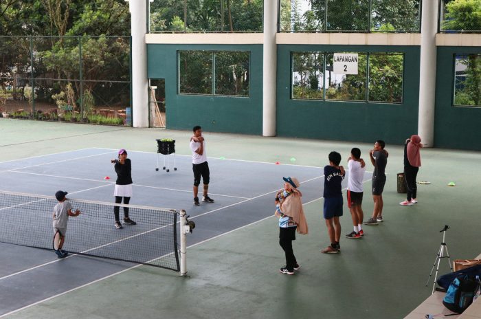 A group of people warming up together on a tennis court.
